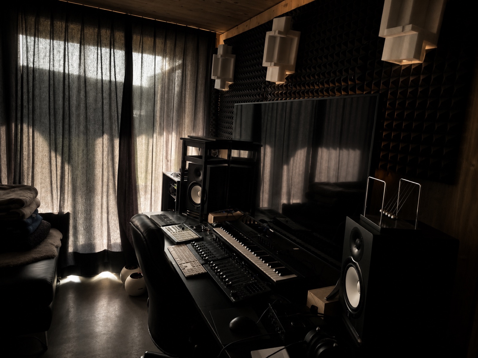 Wide view of the home studio with monitors, keyboard and acoustic treatment
